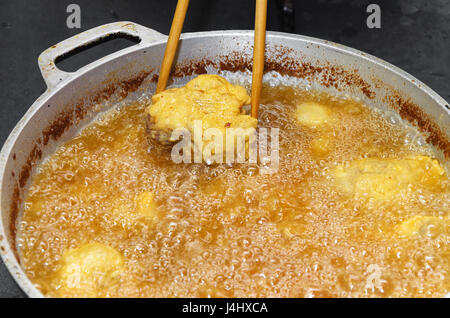 Fisch in einer Pfanne mit kochendem Öl braten. Wir lüften eine Pfanne ein Stück gebratene und panierte Pintado Fisch mit einem Stäbchen. Stockfoto