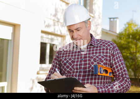 Architekt mit Zwischenablage in Bauarbeiterhelm auf Baustelle Stockfoto