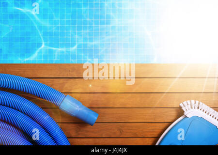 Werkzeuge für die Wartung des Pools auf Holzlatten. Mit Pool mit Wasser und blauen Mosaiken Hintergrund und Sonnenschein. Horizontale Komposition. Ansicht von oben Stockfoto