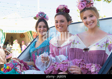 Sevilla, Provinz Sevilla, Andalusien, Südspanien.  Feria de Abril, April Fair.  Drei junge Frauen in ihrem Fiesta Putz gekleidet. Stockfoto