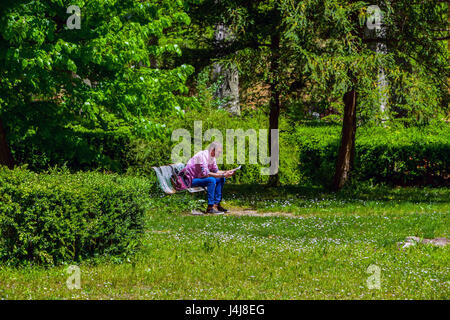 Mann saß im grünen Park, ein Buch zu lesen Stockfoto