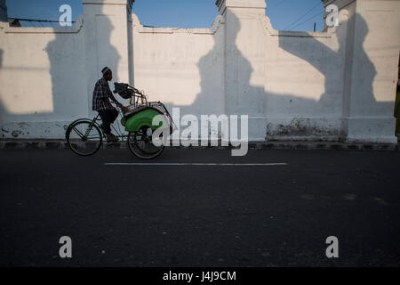 Eine Rikscha-Fahrer mit Kunden in der Stadt Yogyakarta, Java, Indonesien. Stockfoto