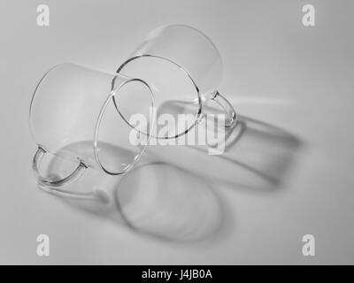 Zwei große Klarglas-Becher für Tee, Schatten, Licht grauer Hintergrund, ein schwarz / weiß Foto in ein Licht-Taste. Stockfoto