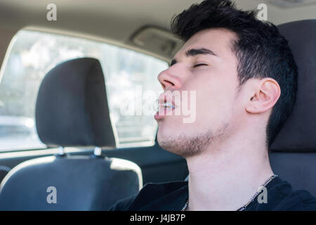 Junger Mann schlafend am Steuer seines Autos fahren Stockfoto