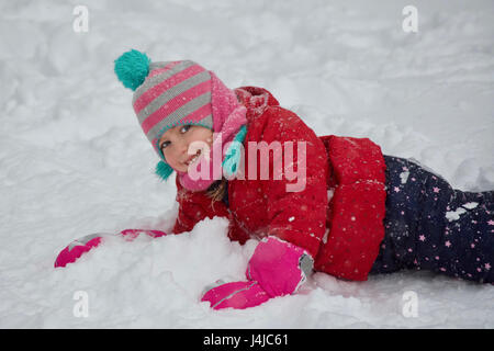 entzückende schulpflichtige Mädchen spielen im Schnee Stockfoto