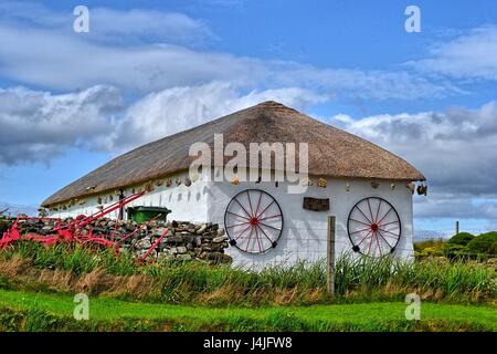 Reetdachhaus auf der Isle Of Skye, mit Wagenrädern an der Wand rockt hängen vom Dach und einer Trockensteinmauer Stockfoto
