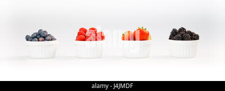 Heidelbeeren, Himbeeren, Erdbeeren und Brombeeren in einer Reihe vor weißem Hintergrund Stockfoto