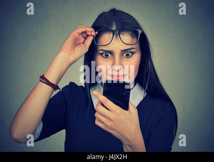 Jungen stören verwirrt Frau mit Brille Handy auf graue Wand Hintergrund isoliert betrachten Stockfoto