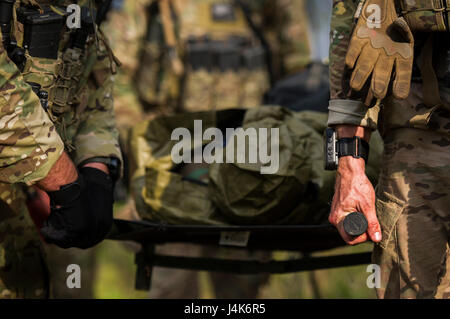 Combat Aviation Berater Studenten mit der 6. Special Operations Squadron tragen einen Wurf durch den Wald während der Operation Raven Klaue am Duke Field, Florida, 27. April 2017. Studenten kamen unter simulierten Beschuss von feindlichen Truppen während ein Prüfpunkt und musste durch den Wald an einem sicheren Ort zu navigieren, während des Tragens eines Unfall mit einem Gewicht von ca. 210 Pfund. (Foto: U.S. Air Force Airman 1st Class Joseph Pick) Stockfoto