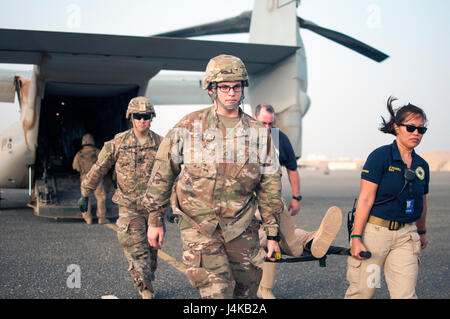 Bewegen Sie PFC. Perry Wolf und Dylan Pulos, bekämpfen Mediziner mit der 86. Combat Support Hospital, sowie Jane Rivera, ein Rettungssanitäter mit Area Support Group - Kuwait, gemeinsame Notdienst einen simulierten Unfall aus einem MV-22 Osprey, während einer gemeinsamen Übung mit Marines aus Marine Medium Tiltrotor Squadron - 364 (VMM-364), am Camp Arifjan, Kuwait, 8. Mai 2017. (US Armee-Foto von Sgt. Christopher Bigelow) Stockfoto