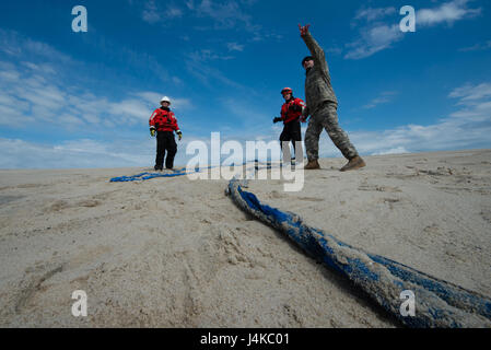 Sgt. 1. Klasse Chris Richards der Connecticut Nationalgarde betont die vorgesehene Flugbahn ein CH-47 Chinook-Hubschrauber, US Coast Guard Chief Warrant Officer Benjamin Jewell und Petty Officer 3rd Class Andrew Hayden von der Coast Guard Cutter Oak Dienstag, 9. Mai 2017, in der Nähe von Chatham, Massachusetts. Der Chinook eine 12.000 Pfund gestrandeter Boje abgeholt und brachte es vor der Küste, wo es von der Küstenwache aufgegriffen wurde. (Foto: US Coast Guard Petty Officer 3rd Class Andrew Barresi) Stockfoto