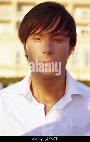 Mann, sehen junge, ernst, Kamera, Portrait, Porträt der eines Mannes, dunkelhaarige, Frisur, draußen, Sommer, Abendlicht, Hintergrund, Hotelanlage, Appartementhaus, Balkone Stockfoto