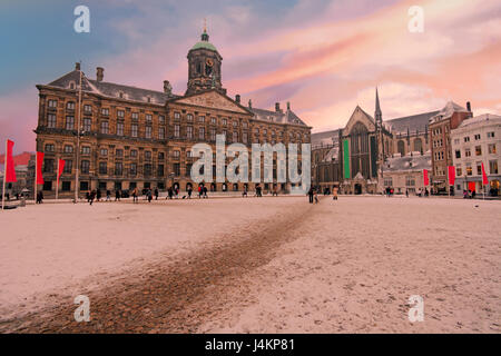 Verschneite Dam in Amsterdam Niederlande im Winter bei Sonnenuntergang Stockfoto