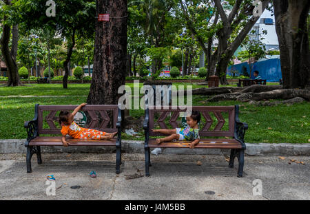 Zwei kleine Kinder spielen auf den Bänken im Park in Saigon Vietnam Stockfoto