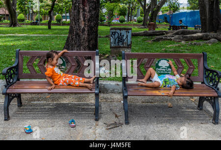 Zwei kleine Kinder spielen auf den Bänken im Park in Saigon Vietnam Stockfoto