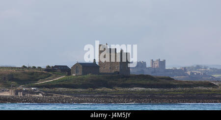 Kapelle St. Cuthbert und Castell Turm auf Inner Farne Island und Bamburgh Castle, auf der Küste von Northumberland in England. Stockfoto