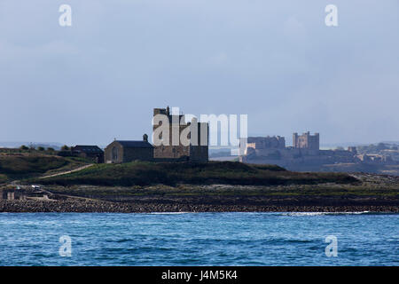 Kapelle St. Cuthbert und Castell Turm auf Inner Farne Island und Bamburgh Castle, auf der Küste von Northumberland in England. Stockfoto