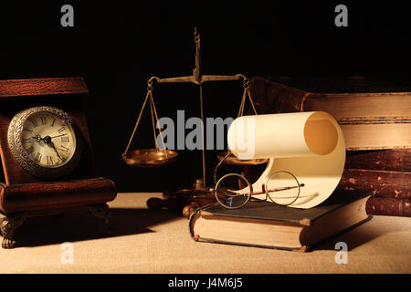 Vintage Holz Uhr in der Nähe von Messing Waage und Bücher auf dunklem Hintergrund Stockfoto