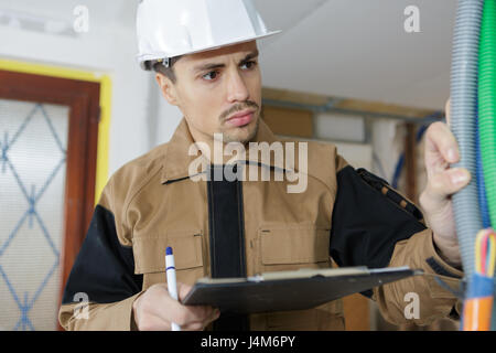 Elektriker Baumeister Ingenieur überprüft Kabel Verdrahtung auf indoor Baustelle Stockfoto