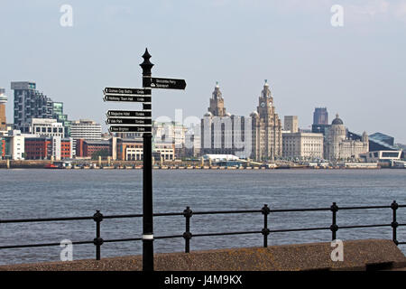 Wegweiser zeigen Wege zu verschiedenen Attraktionen am Seacombe promenade mit Liverpool Waterfront in der Ferne Stockfoto