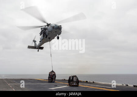 170511-N-UK248-0576-Pazifik (11. Mai 2017) fällt ein MH-60 Seahawk zugewiesen "Wildcards" Hubschrauber Angriff Geschwader 23 ab Fracht auf dem Flugdeck der amphibischen Angriff Schiff USS America (LHA 6) während einer vertikalen Nachschub. Mehr als 1.800 Matrosen und 2.600 Marines zugewiesen, die Amerika amphibische bereit Gruppe (ARG) und der 15. MEU führen derzeit ein Composite Training Unit Übung (COMPTUEX) vor der Küste Süd-Kalifornien für die ARG Einsatz noch in diesem Jahr. Amerika ARG besteht aus Amerika, die amphibische dock Landungsschiff USS Pe Stockfoto