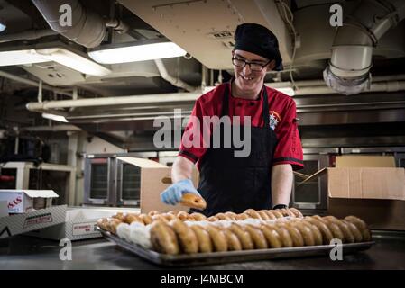 170224-N-IE397-002 NORFOLK, Virginia (24. Februar 2017) kulinarische Spezialist Brandon Bayer, bereitet aus Buckeye, Arizona, Donuts, in der Kombüse an achtern Chaos Deck des Flugzeugträgers USS Dwight D. Eisenhower (CVN-69) (Ike) serviert werden.  Ike ist derzeit Pier Seite der Phase der Erhaltung von der optimierten Flotte Antwort planen (OFRP). (Foto: U.S. Navy Mass Communication Specialist 3. Klasse Christopher A. Michaels) Stockfoto