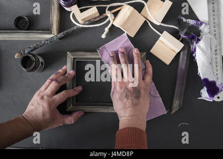 Hände des kaukasischen Künstlers Schleifen Bilderrahmen Stockfoto