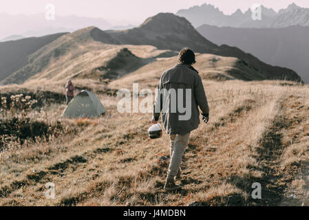 Kaukasischen Mann mit Eimer mit Schnee, Zelt am Berg Stockfoto