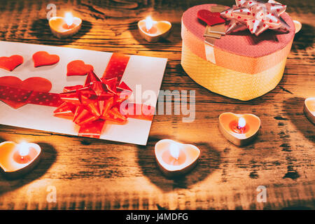 Valentine Kerzen brennen auf Tisch mit Geschenk-Box und Karte Stockfoto