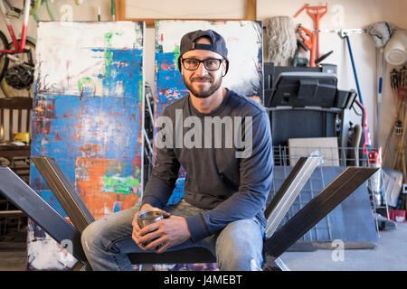 Porträt des kaukasischen Mann sitzt auf Metall-Skulptur Stockfoto