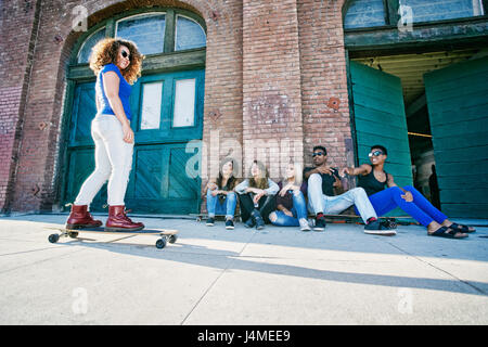 Freunde gerade Frau Skateboarden auf Bürgersteig Stockfoto