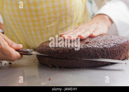 Hispanic Frau schneiden Kuchen mit Messer Stockfoto