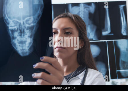 Hispanische Arzt untersucht Röntgenaufnahme des Schädels Stockfoto