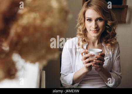 Orientalische Frau sitzt in der Nähe von Fenster Kaffeetrinken Stockfoto