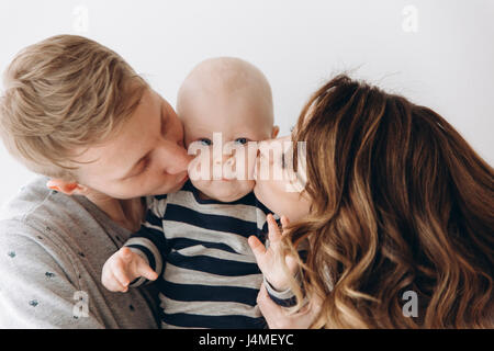 Kaukasische Mutter und Vater Baby Sohn auf Wange küssen Stockfoto