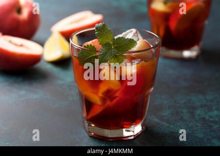 Pfirsich Eistee in ein Glas frische Pfirsiche auf konkrete blauem Hintergrund Stockfoto
