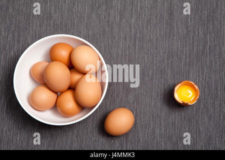 Eiern in einem weißen Teller, ein ganzes Ei neben gebrochen Ei auf dem Tisch Stockfoto