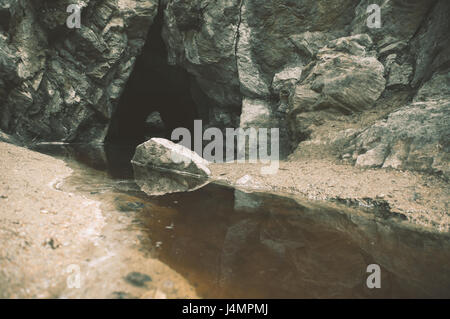 Dunkle Wasser fließt aus der Höhle Stockfoto