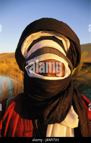 Libyen, Wüste Sahara, Provinz Fezzan, Oase, Mann, Tuareg, Gesichts-Schleier, Porträt Afrika, Nordafrika, Region des Akakus, Sandwüste, wilde Landschaft, Wasser, Wasser, Berber, Schleier, augenfällige Übereinstimmung, Kopfbedeckungen, Litham, Turban, traditionell, desert Sands, Abendlicht, Konzeption, Wärme, Wüste Stamm, Nomad, Schleier, Schutz, Anonymität Stockfoto