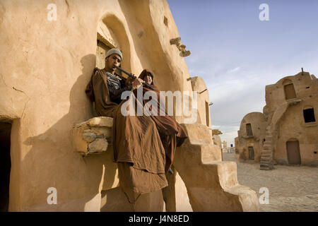 Tunesien, Tataouine, Ksar Sultan Ouled Soltane, Berber, Nordafrika, die Berbersiedlung, Stadt, Siedlung, strukturieren, Ksour, Ghorfa, Speicher-Burg, Fassade, Treppen, Eingang, Urlaubsort, Ziel, Ort von Interesse, Männer, Menschen, Kleidung, traditionell, Musik, Querflöte, Sit, Stockfoto