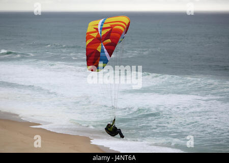 Eine weibliche Gleitschirmpilot Aberta Nova Strand fliegen. Stockfoto