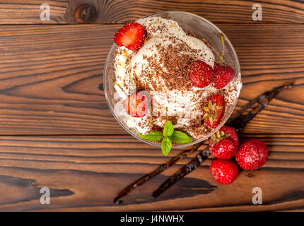 Draufsicht der Erdbeer Rosa Eisportionierer mit bestreut Schokolade, Vanilleschote und frische Erdbeeren auf Holztisch Stockfoto