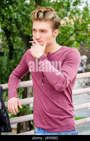 Attraktive blaue Augen, blonde junge Mann Rauchen Stockfoto