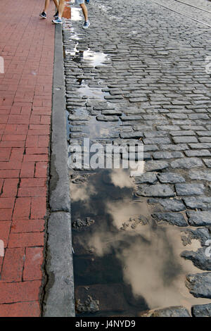 Menschen die Beine treten über lange, Pfützen reflektierende Kopfsteinpflaster auf River Street entlang der berühmten Riverwalk in Savannah, Georgia Stockfoto