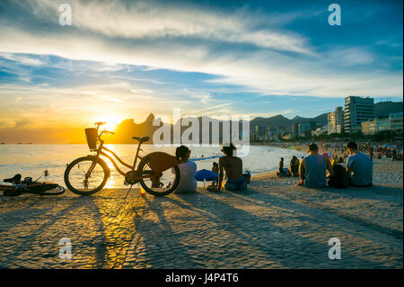 Leute sitzen, den Sonnenuntergang am Arpoador, eine beliebte Sommer-Aktivitäten für Einheimische und Touristen, die in Rio De Janeiro, Brasilien Stockfoto