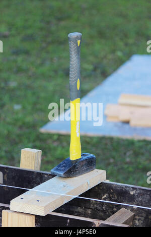 Bau-Werkzeug-Hammer mit einem gelben Griff liegt auf der Schalung Stockfoto