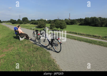 Deutschland, Duisburg, Ruhr Bereich, North Rhine-Westphalia, Duisburg-Rheinhausen, Duisburg-Rheinhausen-Friemersheim, Naturpark Rhein Wiese nach Hause Friemers, Wiese Landschaft, Rhein-Deich, älteres Ehepaar mit dem Fahrrad auf einer Parkbank sitzt und macht eine Pause, kein Modell zu lösen, Stockfoto