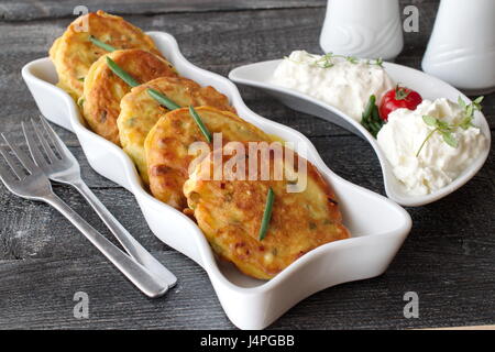 Krapfen mit frischen Frühlingszwiebeln und gekochtes Ei auf einem weißen Teller mit frischen griechischen Joghurt auf einem dunklen Hintergrund aus Holz. Gesundes Frühstück. Gesunde Ernährung-Konzept. Stockfoto