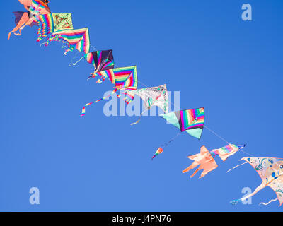 Chioggia, Italien - 30. April 2017: Farbige Drachen fliegen hintereinander in den blauen Himmel an einem Strang hängen. Stockfoto