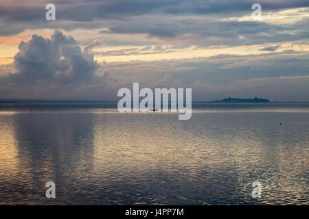 Ein kleines Boot mitten in einem See mit schönen Sonnenuntergang Wolken und Reflexionen Stockfoto